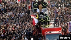 A crowd of mourners surge toward a vehicle carrying wrapped bodies during a funeral service for policemen, people killed in a car bomb explosion, in Egypt's Nile Delta city of Mansoura, about 120 km northeast of Cairo, Dec. 24, 2013.