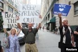 A man holds a sign reading "NYC hearts Muslims" as two other people hold signs reading "Back the Ban" and "Keep Syrians Out" at protests in response to U.S. President Donald Trump's limited travel ban, approved by the U.S. Supreme Court, in New York City, June 29, 2017.