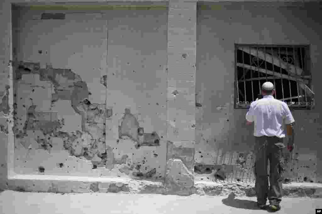 A man surveys the damaged wall of a house after a rocket fired by Palestinian militants hit in Ashdod, Israel, July 14, 2014.