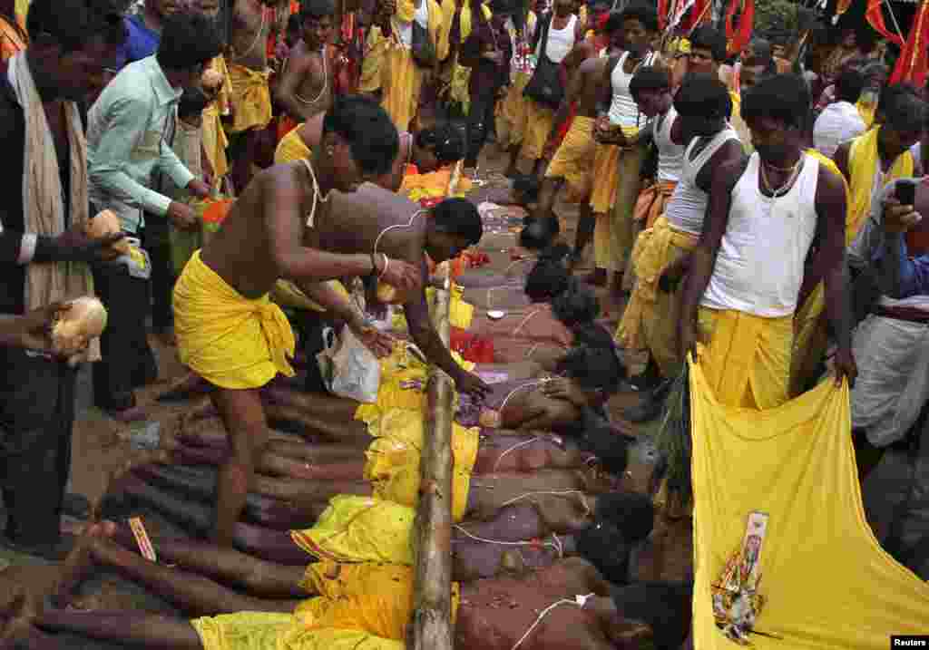 Hindu devotees break coconuts on a wooden log placed on another devotees lying on the ground as they perform a ritual during the "Danda" festival at Kulagarh village in Ganjam district in the eastern Indian state of Odisha.
