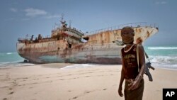 Dalam foto tertanggal 23/9/2012 ini seorang perompak Somalia berdiri di depan kapal Taiwan yang terhempas ke pantai di daerah Hobyo, Somalia. 