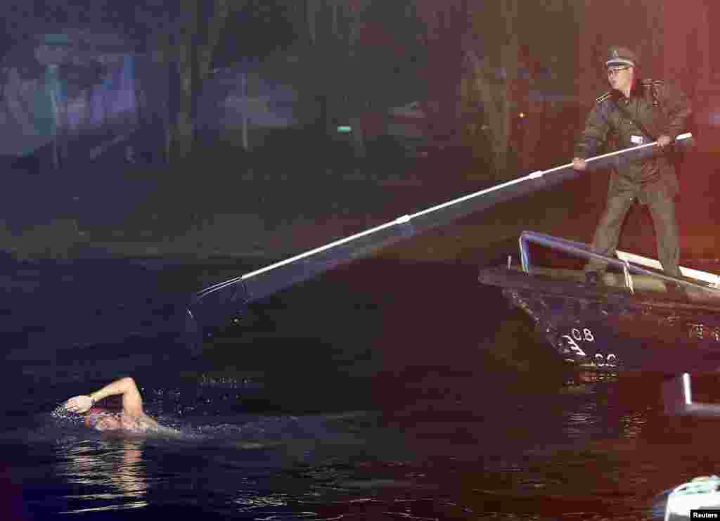 Một nhân viên an ninh cố ngăn một người đàn ông đang bơi đi mất sau khi bị bắt đang bơi trong Hồ Tây, vi phạm quy định của khu du lịch, ở thành phố Hàng Châu, tỉnh Chiết Giang, Trung Quốc.