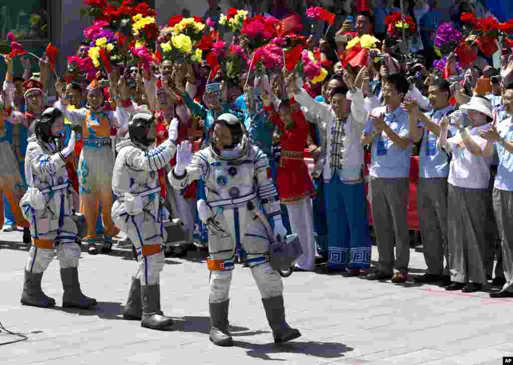 China's astronauts from left, Wang Yaping, Zhang Xiaoguang and Nie Haisheng wave as they leave the Jiuquan satellite launch center near Jiuquan in western China's Gansu province. Three astronauts took flight aboard the spacecraft to the dock with China's Tiangong 1 space lab.