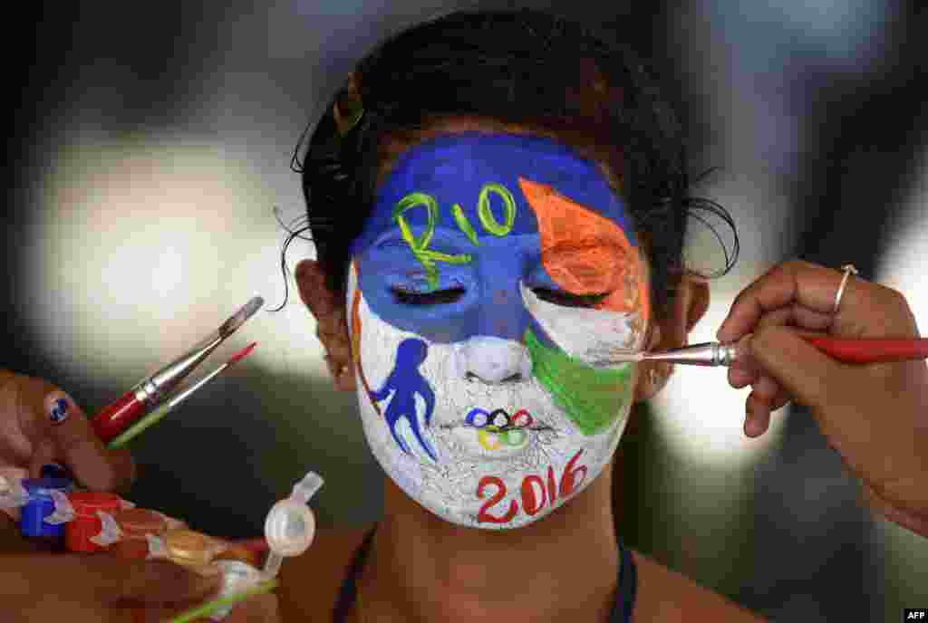Seorang mahasiswi India mencat wajahnya dengan emblem Olimpiade Rio 2016 di Chennai, India.