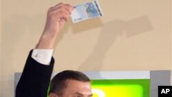 Estonia's Prime Minister Andrus Ansip, lifts a 20 Euro banknote which he withdrew from an ATM cash machine in Tallinn, 01 Jan 2011
