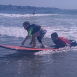 Shaun McLaughlin, 6, who was born without a right foot, gives surfing a try under the watchful eye of AmpSurf volunteers and instructors