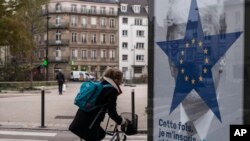 FILE - A cyclist rides past of campaign poster by the Strasbourg municipality for the upcoming European elections in Strasbourg, eastern France, Nov.22, 2018. 