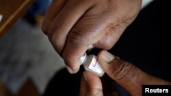 FILE - A member of the vaccination campaign against cholera opens a vial at the Immaculate Conception Hospital in Les Cayes, Haiti, Nov. 8, 2016. 