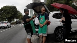 Stefan Weiss (L) and Alexander Costa sell food out of the trunk of a car in Rio de Janeiro, Brazil, Sept. 17, 2018.