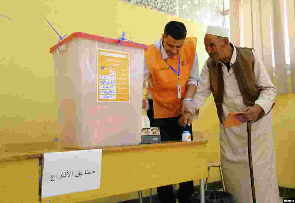 A man dips his finger in ink before casting his vote during a parliamentary election, in Al Bayda, Libya, June 25, 2014.