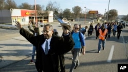 Sekelompok orang berjalan melewati toko-toko yang dibakar di Ferguson, Missouri, dalam protes ke rumah gubernur di Jefferson City yang bertujuan untuk meningkatkan kinerja polisi setelah penembakan Michael Brown, 29 November 2014. 