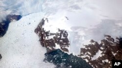 FILE - In this file photo dated Thursday, Aug. 3, 2017, a glacier at left calves icebergs into a fjord off the Greenland ice sheet in southeastern Greenland. (AP Photo/David Goldman, FILE)