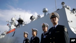 FILE - In this Dec. 7, 2016, photo, Chinese Navy officials stand in front of the ship Daqing, in San Diego. For the second year in a row, China has said it would increase its defense spending by a single-digit percentage.