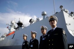 FILE - In this Dec. 7, 2016, photo, Chinese Navy officials stand in front of the ship Daqing, in San Diego.