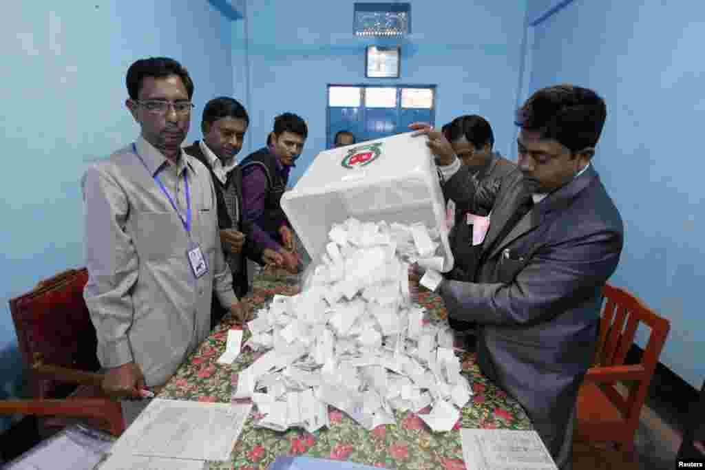 A polling officer pours ballot papers from a box onto a table to count during parliamentary elections in Dhaka, Jan. 5, 2014. 