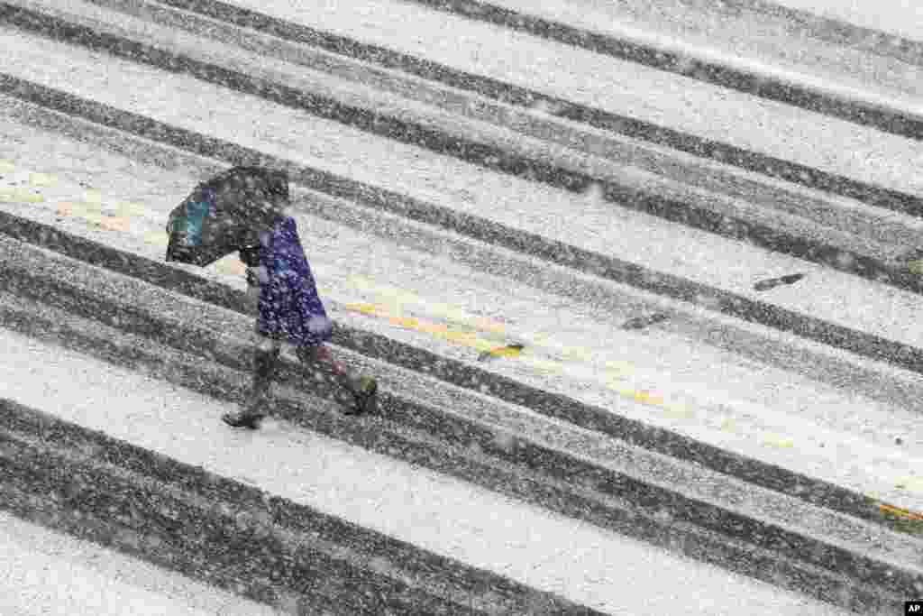 Un piéton traverse la rue couverte de neige lors d&#39;une tempête de neige, à Washington, le 21 mars 2018.