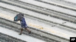 A pedestrian races across the snow-covered and tire-streaked street in Washington during a snow storm, March 21, 2018. 
