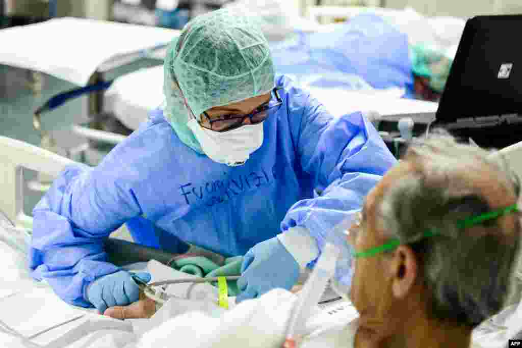 A member of the medical staff comforts a patient infected by the novel coronavirus at the COVID-19 division at the ASST Papa Giovanni XXIII hospital in Bergamo, Italy. 