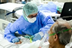 A member of the medical staff comforts a patient infected by the novel coronavirus at the COVID-19 division at the ASST Papa Giovanni XXIII hospital in Bergamo, Italy.