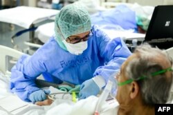A member of the medical staff comforts a patient infected by the novel coronavirus at the COVID-19 division at the ASST Papa Giovanni XXIII hospital in Bergamo, Italy.