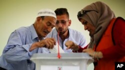 Seorang warga Palestina memasukkan surat suaranya ke dalam kotak suara di sebuah tempat pemungutan suara di Nablus, Tepi Barat, 13 Mei 2017. (AP Photo/Majdi Mohammed)