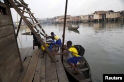 Students who attend a floating school arrive by canoe to school in the Makoko fishing community on the Lagos Lagoon, Nigeria, Feb. 29, 2016.