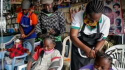 In this Sunday, May 3, 2020 file photo, Gettrueth Ambio, 12, center, Jane Mbone, 7, right, and Hamida Bashir, 3, left, have their hair styled in the shape of the new coronavirus, at the Mama Brayo Beauty Salon in Kibera.