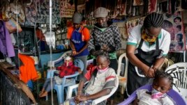 In this Sunday, May 3, 2020 file photo, Gettrueth Ambio, 12, center, Jane Mbone, 7, right, and Hamida Bashir, 3, left, have their hair styled in the shape of the new coronavirus, at the Mama Brayo Beauty Salon in Kibera.