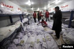 A relative (R) waits while volunteers search for a body of a deceased among people who died due to an intense heat wave, at Edhi Foundation morgue in Karachi, Pakistan, June 22, 2015.