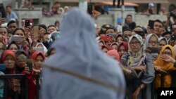 Massa menyaksikan pelaksanaan hukum cambuk di depan sebuah masjid di Banda Aceh, Jumat, 20 April 2018.