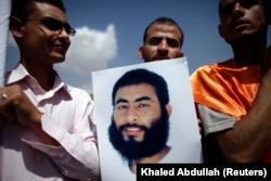 A relative of a Yemeni inmate at Guantanamo Bay holds up his poster during a protest by relatives of detainees to demand their release, outside the U.S. embassy in Sanaa April 1, 2013.
