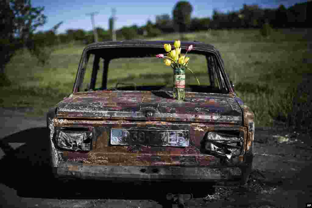 A bouquet of flowers stands on a burned car at the site of clashes between pro-Russia gunmen and the Ukrainian army, four kilometers (2.5 miles) north of Slovyansk, Ukraine, May 7, 2014.