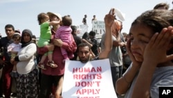 მიგრანტის ტრანსპარანტზე წარწერაა: "ადამიანის უფლებები აქ არ ვრცელდება" 