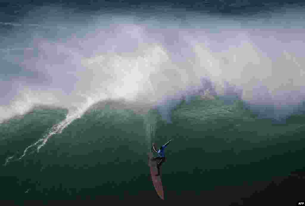 Peselancar AS Nic Lamb beraksi di Praia do Norte di Nazare, Portugal dalam edisi pertama Liga Selancar Dunia Tantangan Nazare (21/12). (AFP/Francisco Leong)