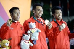 Peraih medali emas Sufriyanto Rindi, Dzar Yulianto Abu, Veddriq Leonardo dari Indonesia merayakan di podium untuk final estafet cepat putra Asian Games ke-18 di Palembang, Senin, 27 Agustus 2018. (Foto: AP/Vincent Thian)