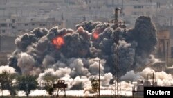 FILE - Smoke and flames rise from an Islamic State fighters' position in the town of Kobani during airstrikes by the U.S.-led coalition seen from the outskirts of Suruc, near the Turkey-Syria border, Oct. 28, 2014. 