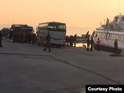 As dawn breaks, refugees and other migrants board boats to Turkey with few onlookers, as the time of their departure was kept secret from most in Lesbos, Greece, April 4, 2016. (Courtesy photo by Ali el Khalaf)