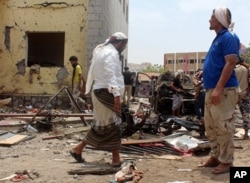Fighters loyal to the government gather at the site of a suicide car bombing in Yemen’s southern city of Aden, Yemen, Aug. 29, 2016. T