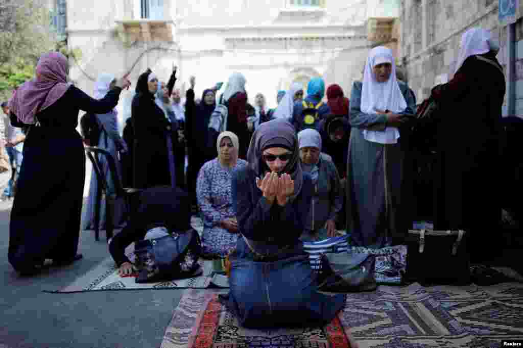 Palestinian women pray as others shout slogans outside the compound known to Muslims as Noble Sanctuary and to Jews as Temple Mount, in Jerusalem&#39;s Old City. Yon fanm palestinyen kap priye pandan lòt moun yo ap voye pawòl piman bouk sou Izrayèl&nbsp; devan yon moske yo rele Noble Sanctuary ki kote a kot ak yon tanp jwif&nbsp; nan Jerizalèm.