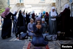 Palestinian women pray as others shout slogans outside the compound known to Muslims as Noble Sanctuary and to Jews as Temple Mount, in Jerusalem's Old City July 27, 2017.
