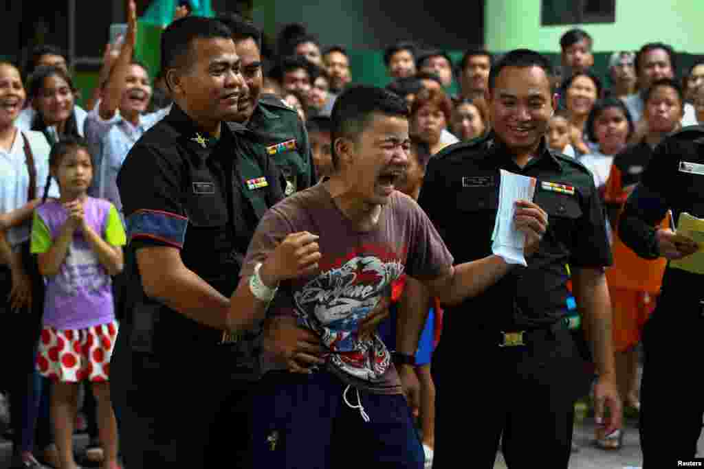 Seorang pemuda (tengah) merasa lega setelah dinyatakan bebas dari wajib militer pada undian yang dilakukan di sekolah Klong Toey, kawasan kumuh di pinggiran Bangkok, Thailand.