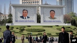 People walk beneath portraits of late leaders, Kim Il Sung, left, and Kim Jong Il, in Pyongyang, North Korea, April 18, 2017.