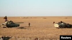 Armored vehicles take position in the middle of a desert near Syria border, Iraq in this still image taken from a video obtained by Reuters on Nov. 23, 2017. (Hashid Shaabi/Handout via Reuters TV) 