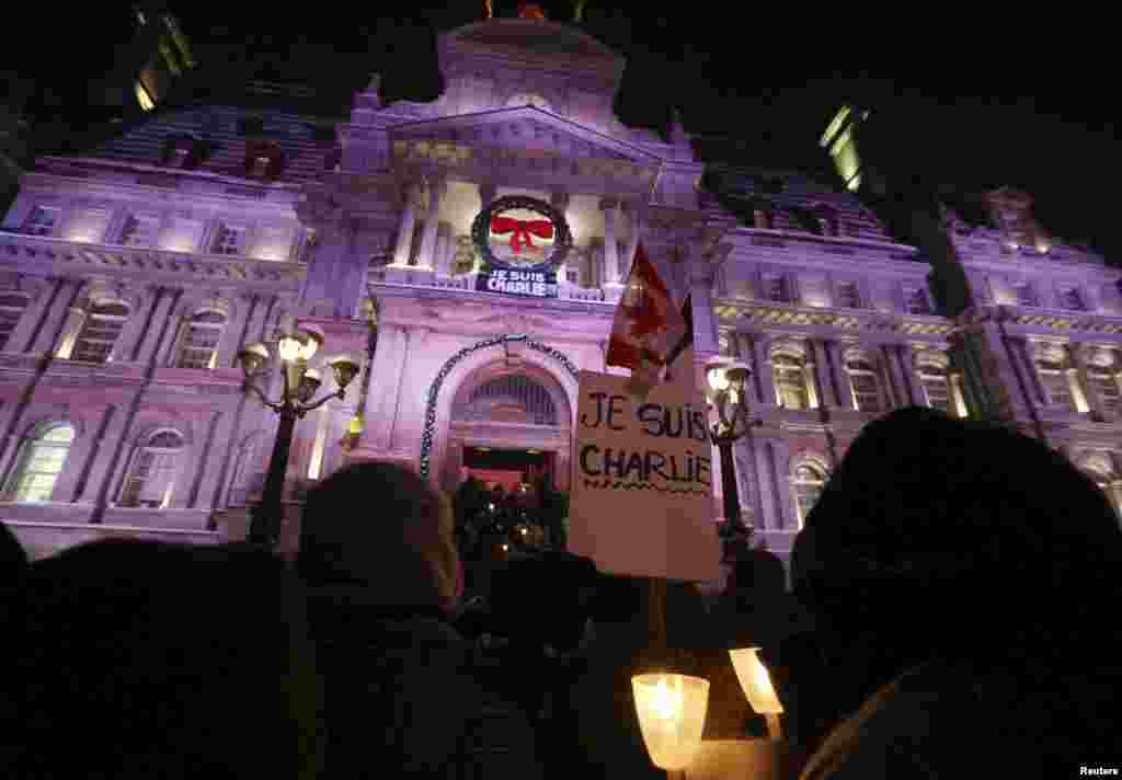 People participate in a vigil to pay tribute to the victims of a shooting, by gunmen at the offices of weekly satirical magazine Charlie Hebdo in Paris, in front of City Hall in downtown Montreal, Jan. 7, 2015. 