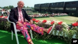 FILE - Tennis commentator Bud Collins, known for his flashy attire, displays a pair of brightly colored trousers as he sits overlooking the outside courts at Wimbledon, England, June 30, 1993. Collins died Friday at his home in Massachusetts; he was 86.