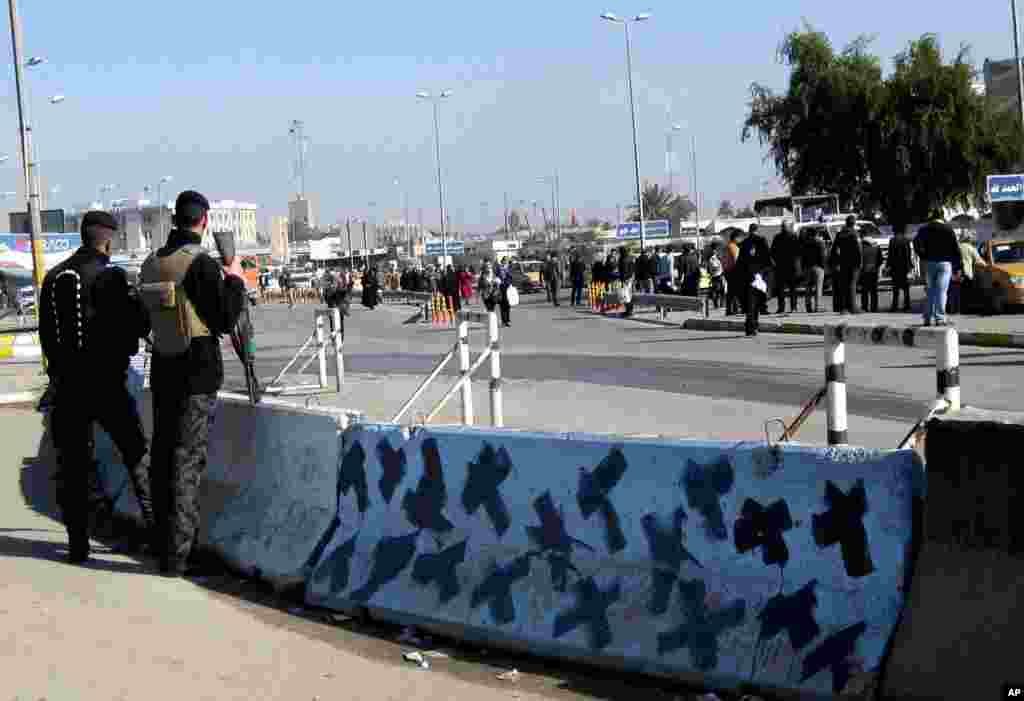 Petugas keamanan Irak berjaga-jaga di lokasi serangan bom di Baghdad (12/1). (AP/Hadi Mizban)