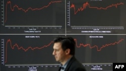 Seorang pria melewati papan indeks bursa saham di Athena, Yunani (foto: dok). Krisis Yunani mengimbas harga saham dunia yang anjlok hari Senin (29/6).