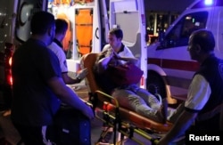 An injured woman covers her face as she is carried by paramedics into ambulance at Istanbul Ataturk Airport, Turkey, following explosions at the facility, June 28, 2016.