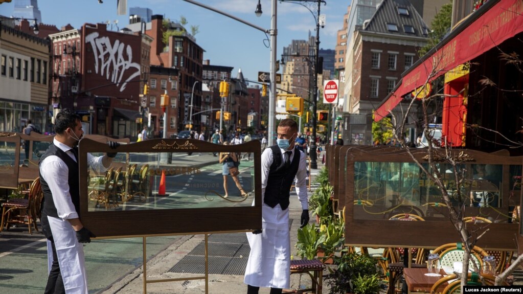 Waiters at a restaurant adjust social distancing screens outside for outdoor seating that follows current health guidelines to slow the spread of Coronavirus (COVID-19) at a restaurant in New York City, June 25, 2020. (Reuters)