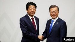 South Korean President Moon Jae-in shakes hands with Japanese Prime Minister Shinzo Abe during their meeting in Pyeongchang, South Korea, Feb. 9, 2018.